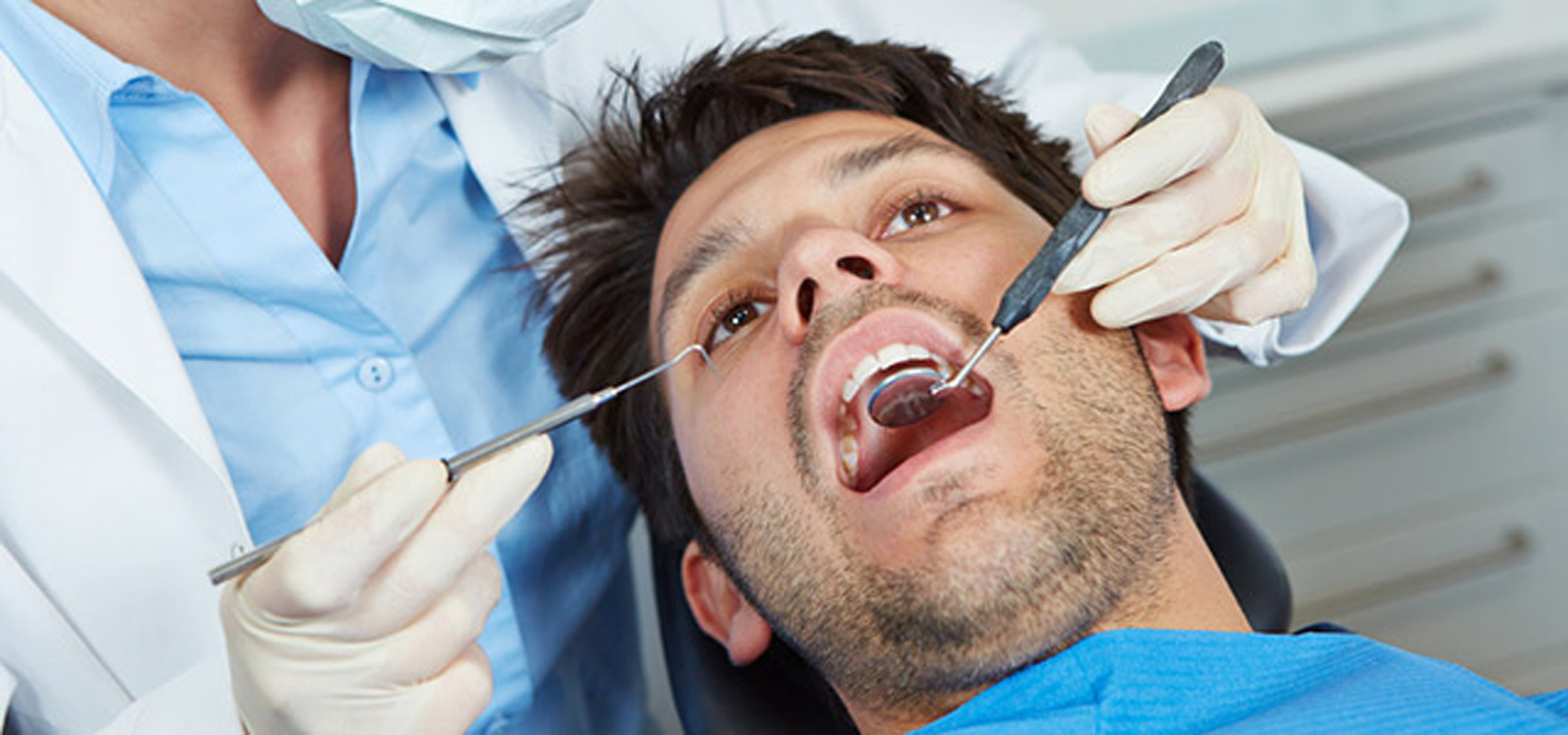 Zahnärztin mit Sonde und Spiegel am Patient